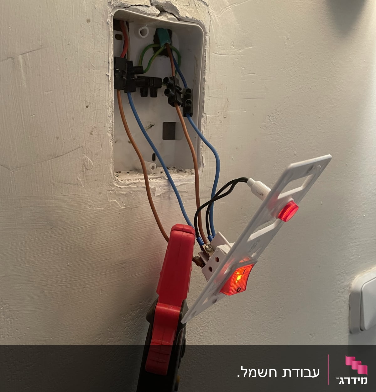 חוטי חשמל מחוברים לשקע בקיר עם כלי עבודה